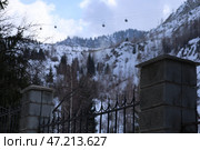 Забор в горах Алматы на фоне канатной дороги зимой. Редакционное фото, фотограф Евгений Митрофанов / Фотобанк Лори