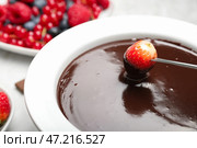 Окунуть вкусную клубнику в миску с шоколадным фондю на столе, крупным планом. Стоковое фото, фотограф Pixel_shot / Фотобанк Лори