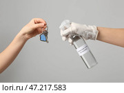 Люди дезинфицируют ключ от дома на сером фоне. Стоковое фото, фотограф Pixel_shot / Фотобанк Лори