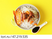 Чаша с вкусной рисовой лапшой и мясом на цветном фоне. Стоковое фото, фотограф Pixel_shot / Фотобанк Лори