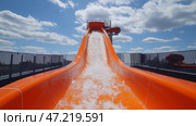 Exciting water slide experience at a summer amusement park on a sunny day with fluffy clouds. Захватывающие водные горки в летнем парке развлечений в солнечный день с пушистыми облаками. Стоковое AI-изображение, AI-художник Katsiaryna Repich / Фотобанк Лори