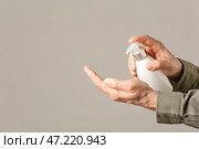 Человек с дезинфицирующим средством на сером фоне. Стоковое фото, фотограф Pixel_shot / Фотобанк Лори
