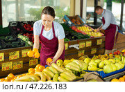 Woman selelr of vegetable department store is replenishing showcase with oranges. Стоковое фото, фотограф Яков Филимонов / Фотобанк Лори