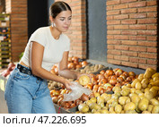 Young female customer made beeline for fresh produce section, pick potato and puts it in bag. Стоковое фото, фотограф Яков Филимонов / Фотобанк Лори