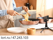 Молодая женщина готовит вкусную пасту во время записи видеоурока на кухне. Стоковое фото, фотограф Pixel_shot / Фотобанк Лори