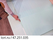 A male construction worker carefully lays underlayment on the floor to ensure laminate flooring. Стоковое фото, фотограф Виктория Тельминова / Фотобанк Лори
