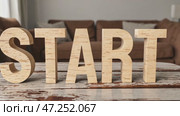 Wooden letters forming the word "START" are arranged on a rustic wooden table with a softly blurred background. Стоковое AI-видео, аниматор Ирина Старикова / Фотобанк Лори