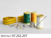 Катушки с нитками, измерительная лента, английские булавки и наперсток на сером фоне. Стоковое фото, фотограф Pixel_shot / Фотобанк Лори