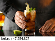 Мужчина-бармен со стаканом вкусного коктейля Cuba Libre на столе в баре. Стоковое фото, фотограф Pixel_shot / Фотобанк Лори