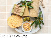 Доска с кусками мыла, оливками, губками, морской солью и мочалкой на фоне бежевой плитки. Стоковое фото, фотограф Pixel_shot / Фотобанк Лори