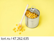 Жестяная банка и ложка с кукурузными зернами на желтом фоне. Стоковое фото, фотограф Pixel_shot / Фотобанк Лори