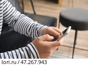 Молодой человек пользуется мобильным телефоном в офисе, крупным планом. Стоковое фото, фотограф Pixel_shot / Фотобанк Лори