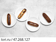 Тарелки с вкусными шоколадными эклерами на светлом фоне. Стоковое фото, фотограф Pixel_shot / Фотобанк Лори