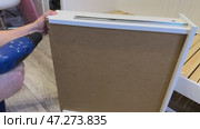 The man is assembling pull-out shelves for the sofa bed. He installs the bottom of the shelf and secures it with screws. Self-assembly of furniture. Стоковое видео, видеограф Vadzim Yakubovich / Фотобанк Лори