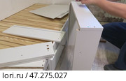 The man is assembling pull-out shelves for the sofa bed from wooden panels. He connects them with furniture hardware. Стоковое видео, видеограф Vadzim Yakubovich / Фотобанк Лори