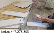 The man lays out wooden panels for assembling pull-out shelves. Linen shelves for the sofa bed. Стоковое видео, видеограф Vadzim Yakubovich / Фотобанк Лори