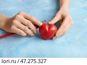 Женские руки с красным сердцем и стетоскоп на цветном фоне. Кардиологическая концепция. Стоковое фото, фотограф Pixel_shot / Фотобанк Лори