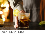 Мужчина-бармен со стаканом вкусного коктейля Cuba Libre на столе в баре. Стоковое фото, фотограф Pixel_shot / Фотобанк Лори