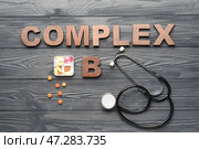 Текст COMPLEX B со стетоскопом и таблетками на фоне темного дерева. Стоковое фото, фотограф Pixel_shot / Фотобанк Лори