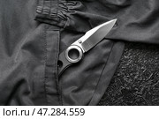 Складной перочинный нож с прорезиненной ручкой на фоне черного костюма. Стоковое фото, фотограф Pixel_shot / Фотобанк Лори