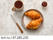 Тарелка с вкусными круассанами и чашкой чая на светлом фоне. Стоковое фото, фотограф Pixel_shot / Фотобанк Лори