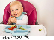 Baby food. The first meal. Feeding the baby. A cute little kid eats vegetables. Healthy food. The child is sitting on a high chair for feeding. Fresh vegetables and fruits. Стоковое фото, фотограф Photojuli / Фотобанк Лори