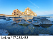 Morning on Lake Baikal during spring ice drift. View of famous Shamanka Rock - natural landmark of Olkhon Island. Bay is covered with thin transparent crust of blue ice. Scenic landscape. Change seasons. Стоковое фото, фотограф Виктория Катьянова / Фотобанк Лори