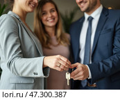 Real Estate Agents Finalize a Home Purchase by Handing Over Keys in a Modern Office Setting With Happy Clients in the Background. Стоковое AI-изображение, AI-художник Sergey Grishin / Фотобанк Лори