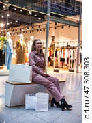 Shopping Experience Brings Joy to Woman Seated in Modern Mall Environment Filled With Light. Стоковое фото, фотограф Aleksandr Golubev / Фотобанк Лори