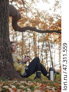 Enjoying a Warm Drink Under a Sprawling Tree During a Golden Autumn Afternoon. Стоковое фото, фотограф Aleksandr Golubev / Фотобанк Лори