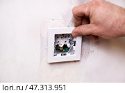 Installing an electrical outlet . The wall indicates that renovation work is underway. Стоковое фото, фотограф Виктория Тельминова / Фотобанк Лори