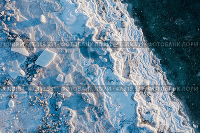Winter aerial photograph of the icy coast and ice floes in sea water. Top view of the freezing sea. Nature of the Extreme North. Cold frosty winter weather. Harsh arctic climate. Natural background. Стоковое фото, фотограф Андрей Степанов / Фотобанк Лори