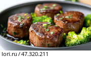 Searing garlic butter steak bites in a skillet with roasted broccoli as a delicious and satisfying low carb dinner option. Стоковое AI-изображение, AI-художник 123 12 / Фотобанк Лори
