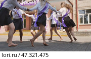 Female graduates wearing sashes and holding hands, dancing barefoot in the schoolyard, celebrating their last school day. Стоковое фото, фотограф Mikhail Davidovich / Фотобанк Лори
