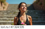 Under the bright sun, a woman ascends outdoor stairs while holding vibrant flowers. Her expression reflects happiness and serenity, making the moment uplifting. Стоковое AI-изображение, AI-художник Sergey Grishin / Фотобанк Лори