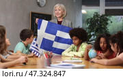 in entertaining geography lesson, children look at flag of Greece with interest. Стоковое видео, видеограф Яков Филимонов / Фотобанк Лори