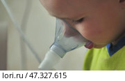The kid is breathing with an inhaler and watching a cartoon. Стоковое видео, видеограф Mikhail Davidovich / Фотобанк Лори