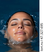 Woman relaxing in water with serene expression at a spa setting. Женщина наслаждается моментом спокойствия, плавая в воде, ее глаза закрыты, а лицо безмятежно. Мягкие пузырьки окружают ее, усиливая успокаивающую атмосферу спа-процедур. Стоковое AI-изображение, AI-художник Katsiaryna Repich / Фотобанк Лори