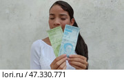 Venezuelan girl holds in her hands the money of her country. Inflation concept. Стоковое видео, видеограф Mikhail Davidovich / Фотобанк Лори