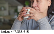 Happy senior woman having a coffee break and thinking at home. Face of an elderly lady feeling nostalgic while having tea during retirement. Elderly woman thinking, decision with wellness and calm. Стоковое видео, видеограф Марина Демидюк / Фотобанк Лори