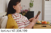 Senior woman having breakfast sitting in bed, drinking tea, enjoying her morning at home. Old lady eating from tray and using phone. Elderly female in pajamas relaxing with cup of coffee in a bedroom. Стоковое видео, видеограф Марина Демидюк / Фотобанк Лори
