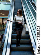 Woman on Escalator in Modern Shopping Mall Exploring the Latest Trends and Styles. Стоковое фото, фотограф Aleksandr Golubev / Фотобанк Лори