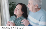Old couple have breakfast sitting at the kitchen table, drink coffee. Embracing elderly man and woman. Senior couple together marriage in retirement talking with each other. Enjoying the pleasantries. Стоковое видео, видеограф Марина Демидюк / Фотобанк Лори