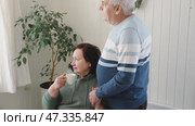Old couple have breakfast sitting at the kitchen table, drink coffee. Embracing elderly man and woman. Senior couple together marriage in retirement talking with each other. Enjoying the pleasantries. Стоковое видео, видеограф Марина Демидюк / Фотобанк Лори