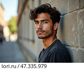 A young man leans against a textured wall in a city street, showcasing his stylish hair and confident expression during a sunny day. The urban backdrop adds to the moment\'s vibrancy. Стоковое AI-изображение, AI-художник Sergey Grishin / Фотобанк Лори