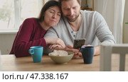Loving mature couple interactions at home. Husband and wife hugging, holding hands and drinking morning coffee together. Man and woman talk about plans for weekend. Natural lighting. Intimate moments. Стоковое видео, видеограф Марина Демидюк / Фотобанк Лори