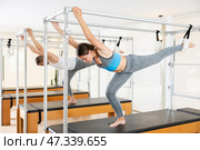 Concentrated girl practicing pilates on trapeze table at group training. Стоковое фото, фотограф Яков Филимонов / Фотобанк Лори