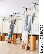 Man hanging upside down on Pilates trapeze table in fitness studio. Стоковое фото, фотограф Яков Филимонов / Фотобанк Лори