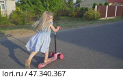 A little girl in the village rides a scooter. Стоковое видео, видеограф Mikhail Davidovich / Фотобанк Лори