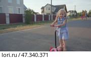 A little girl in the village rides a scooter. Стоковое видео, видеограф Mikhail Davidovich / Фотобанк Лори